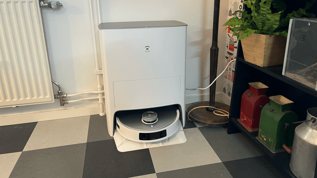 Robotdammsugaren Ecovacs Deebot T20 Omni i sin dockningstation. Står i ett hörn av ett rum.